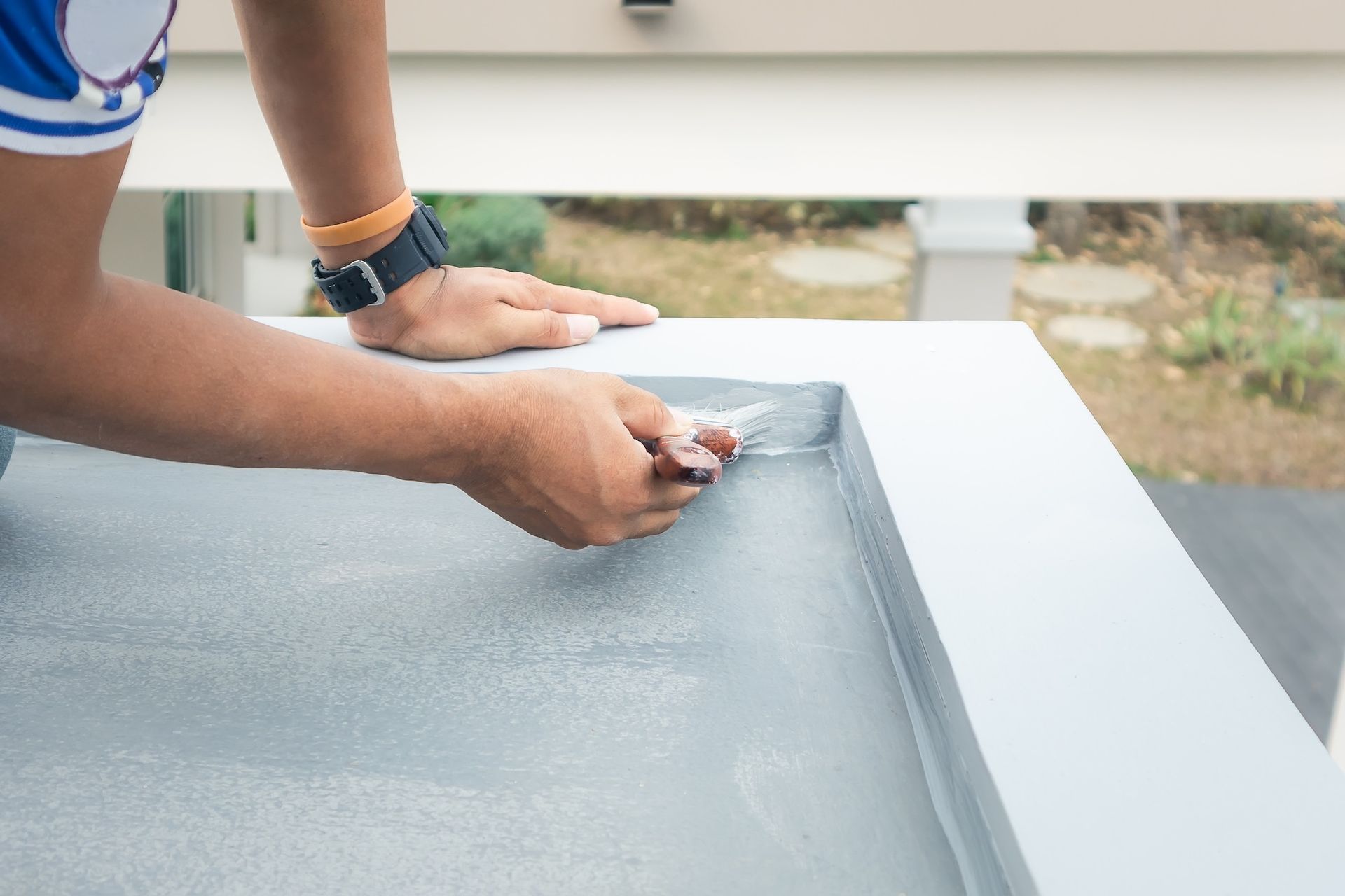 Person painting a gray surface on an outdoor table with a brush— Matty Stewart Painting & Decorating in Mudgee, NSW