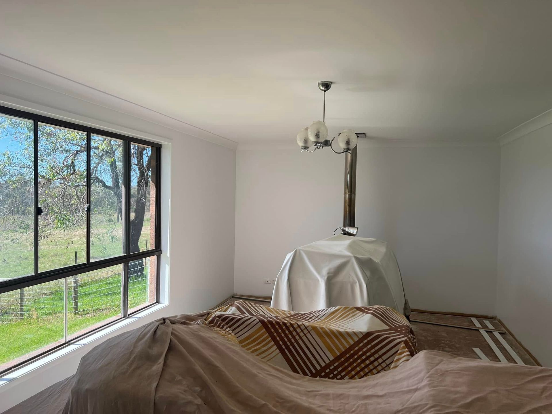 Empty White Room with Large Window and Covered Furniture — Matty Stewart Painting & Decorating in Mudgee, NSW