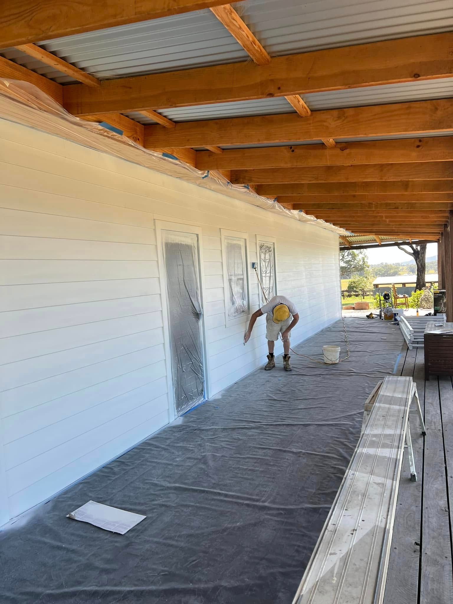 Worker Painting a White Building Exterior Under a Covered Walkway — Matty Stewart Painting & Decorating in Orange, NSW
