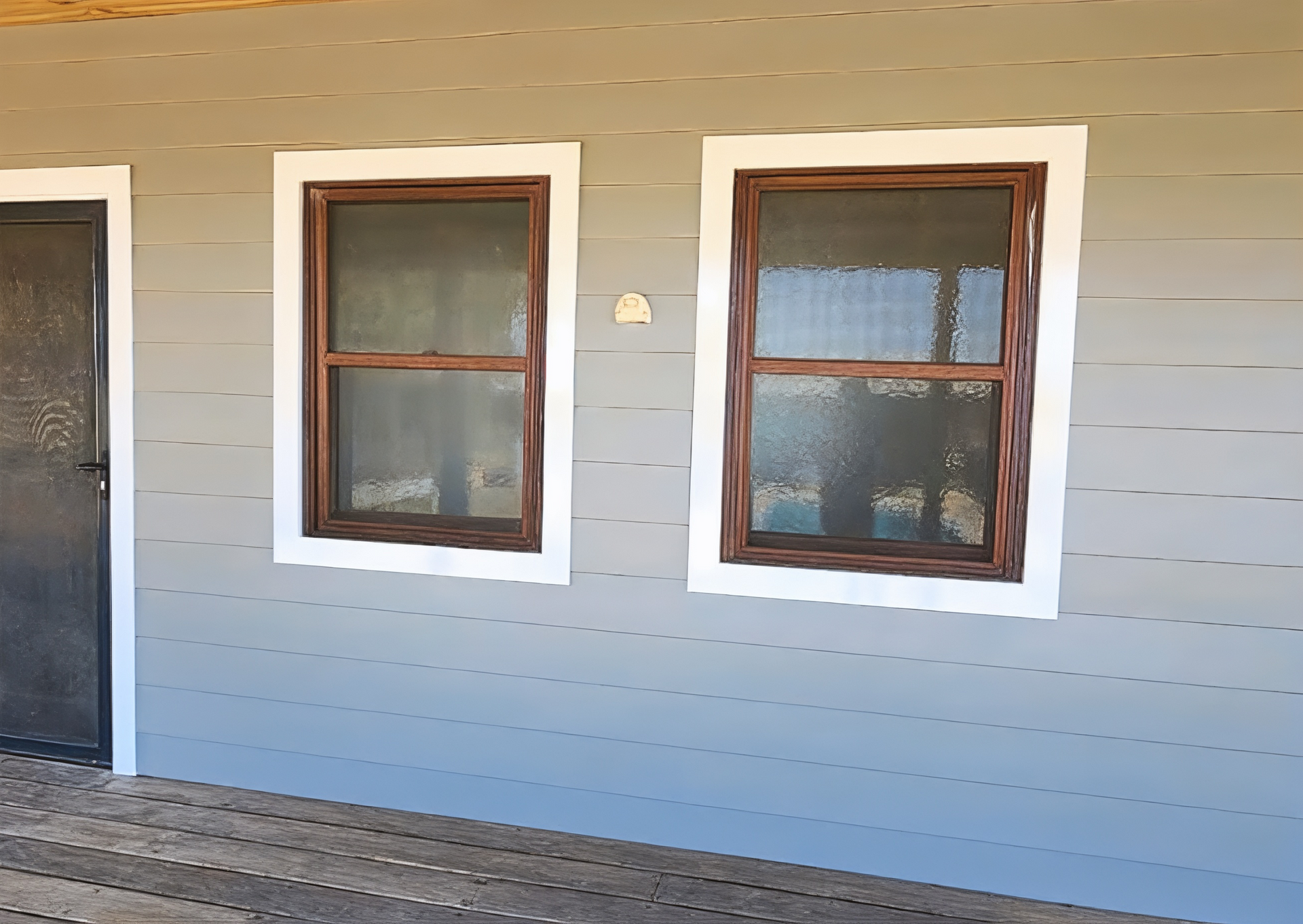 Exterior of a beige house wall with two brown-trimmed windows and a dark door on the left — Matty Stewart Painting & Decorating in Mudgee, NSW