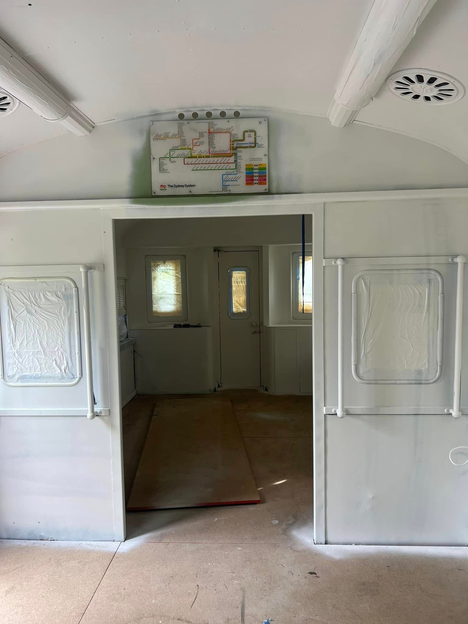 Open Doorway in A White Train Car Interior with Small Map Sign Above It — Matty Stewart Painting & Decorating in Orange, NSW