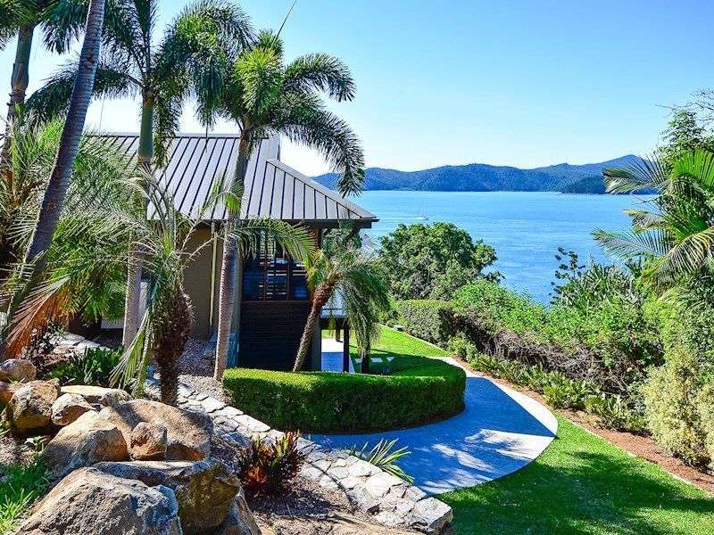 Tropical seaside villa with palm trees, a winding path, and blue ocean views