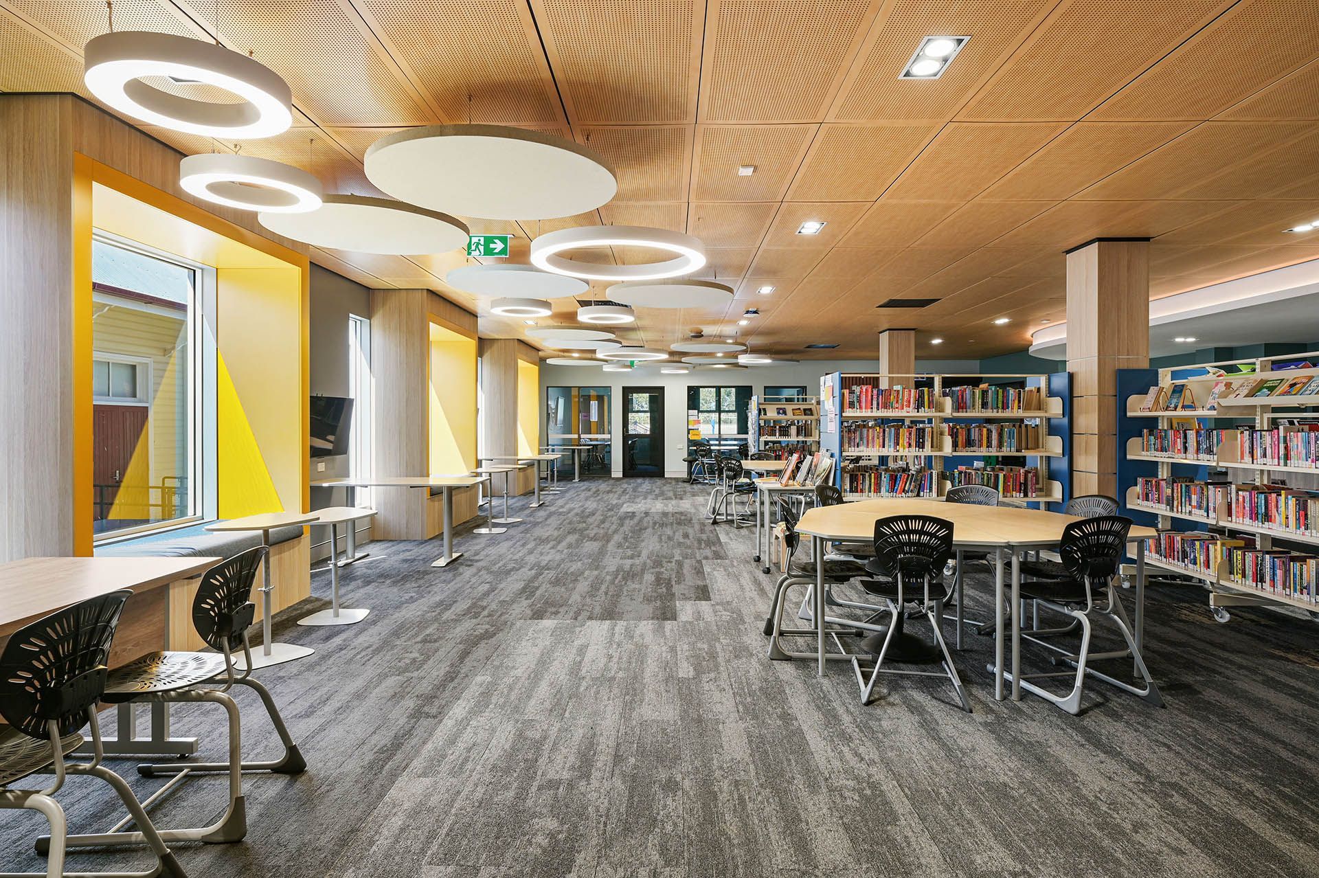 Modern library interior with tables, bookshelves, computers, and circular ceiling lights