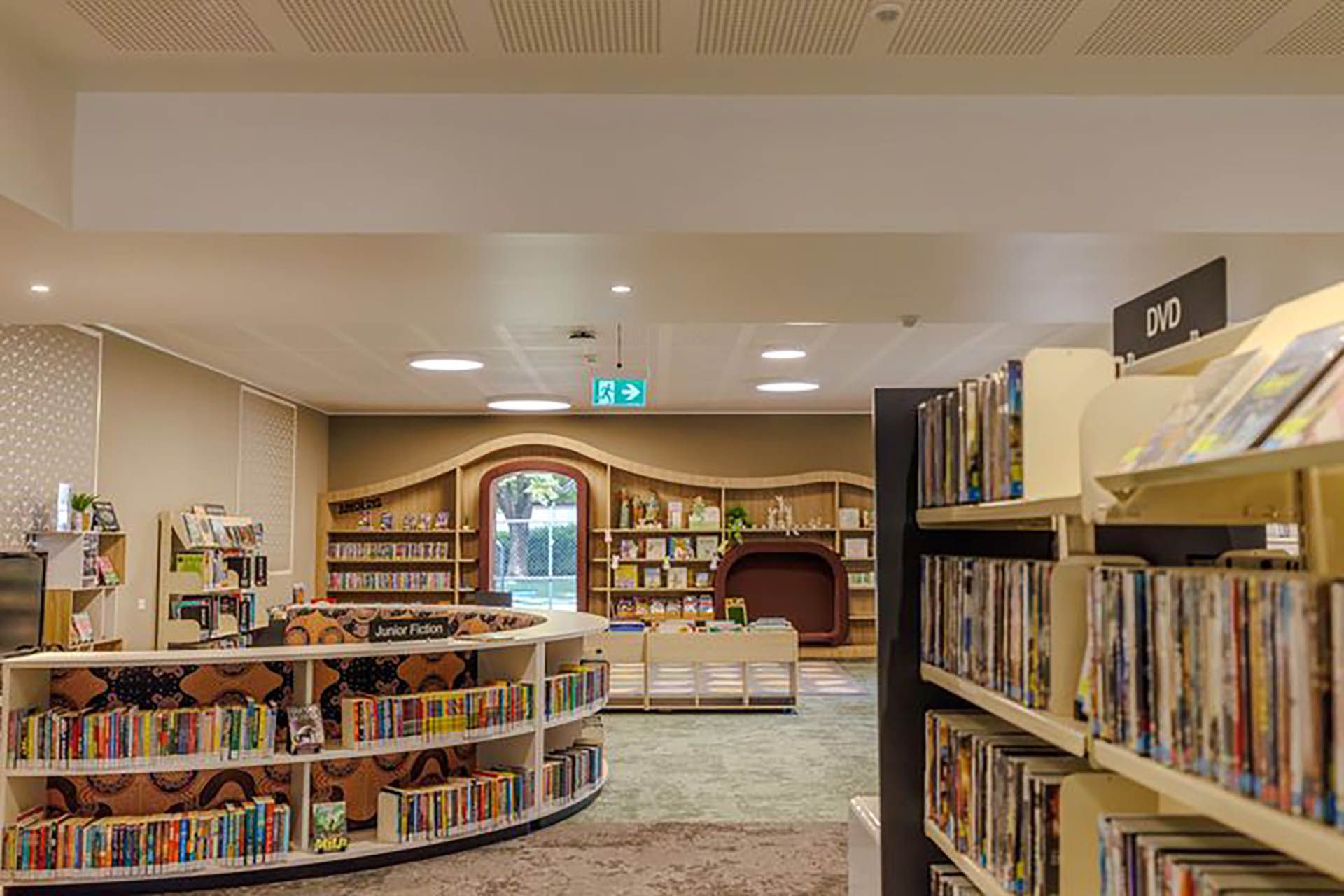 Children’s library with bookshelves, reading tables, and a circular book display under warm lighting