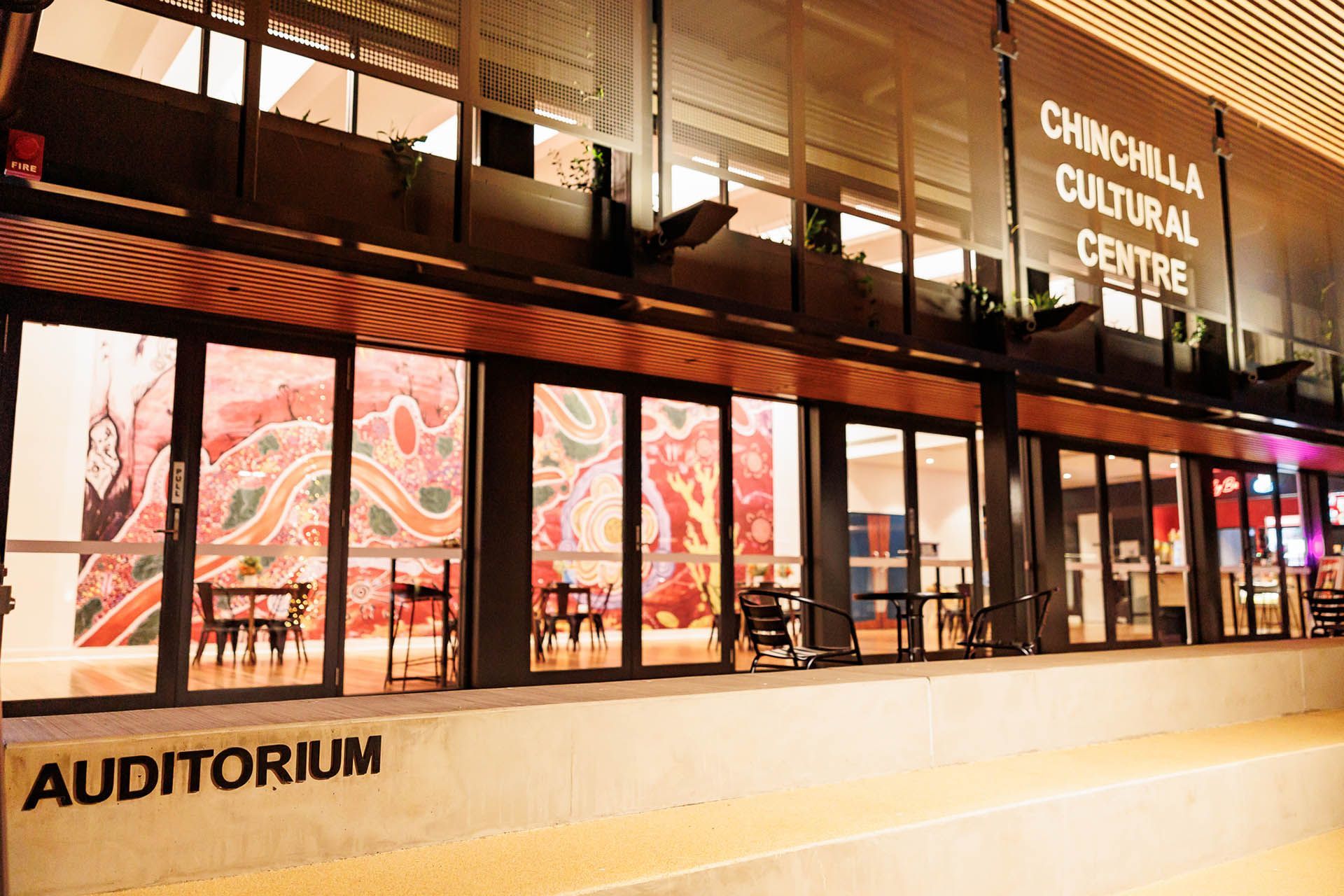 Chinchach Cultural Center auditorium entrance at night, with illuminated windows and colorful interior artwork