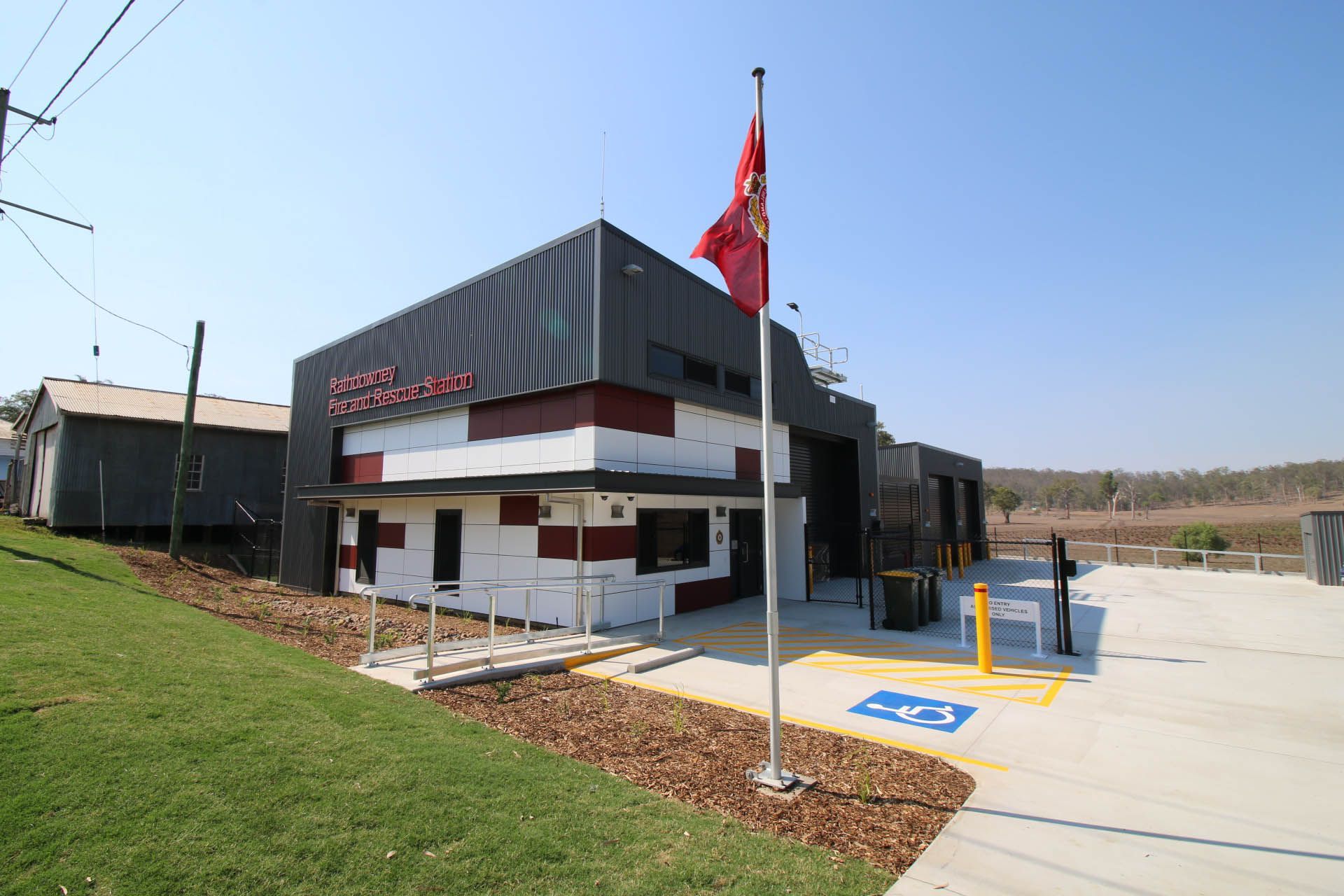 Modern building with a red flag, small parking area, and blue accessible parking spaces
