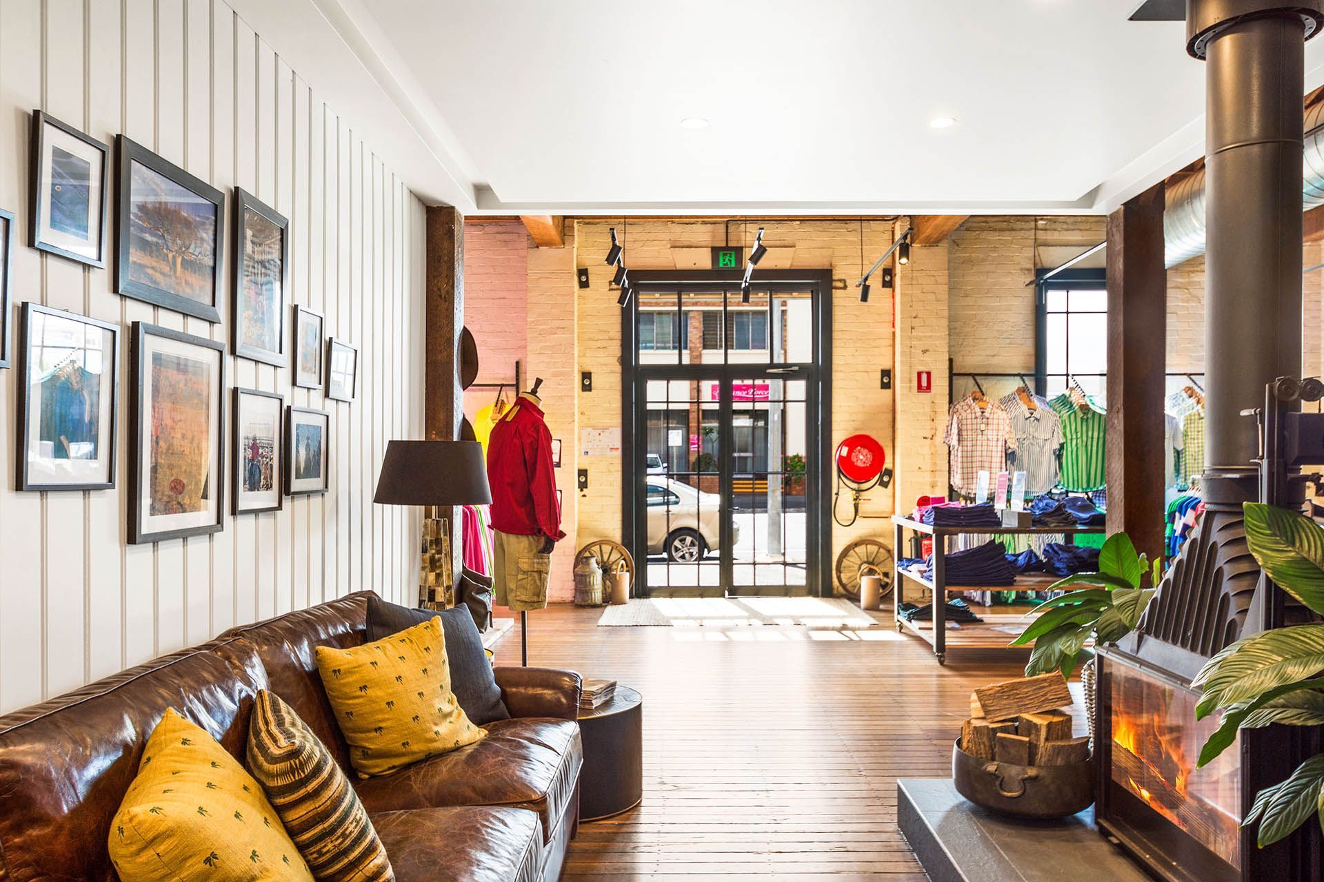 Cozy lobby with leather sofa, framed art, plants, and a glass entrance in the background