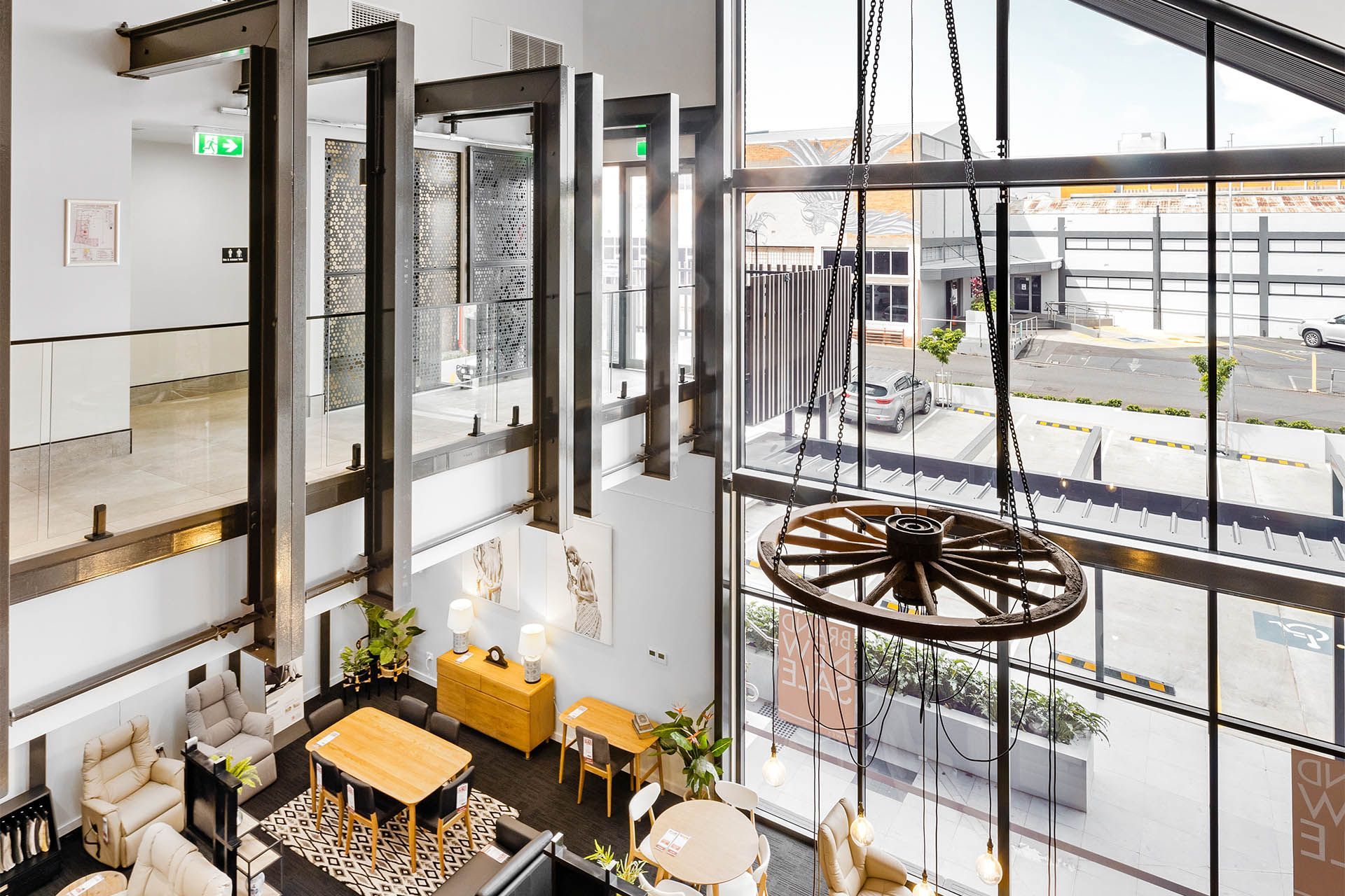 Bright lobby with glass walls, hanging wheel sculpture, and seating area in a modern building