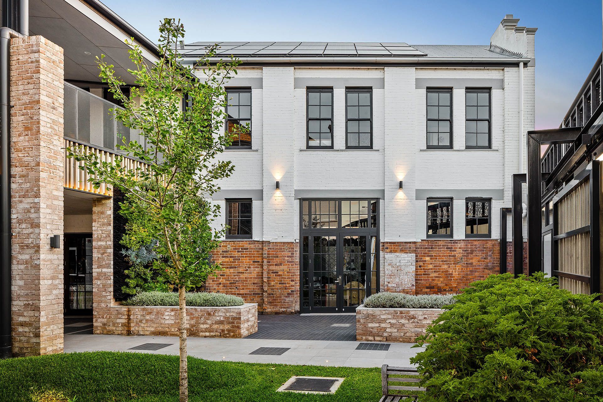 Modern two-story white brick house with black-framed windows, brick accents, and a landscaped front yard
