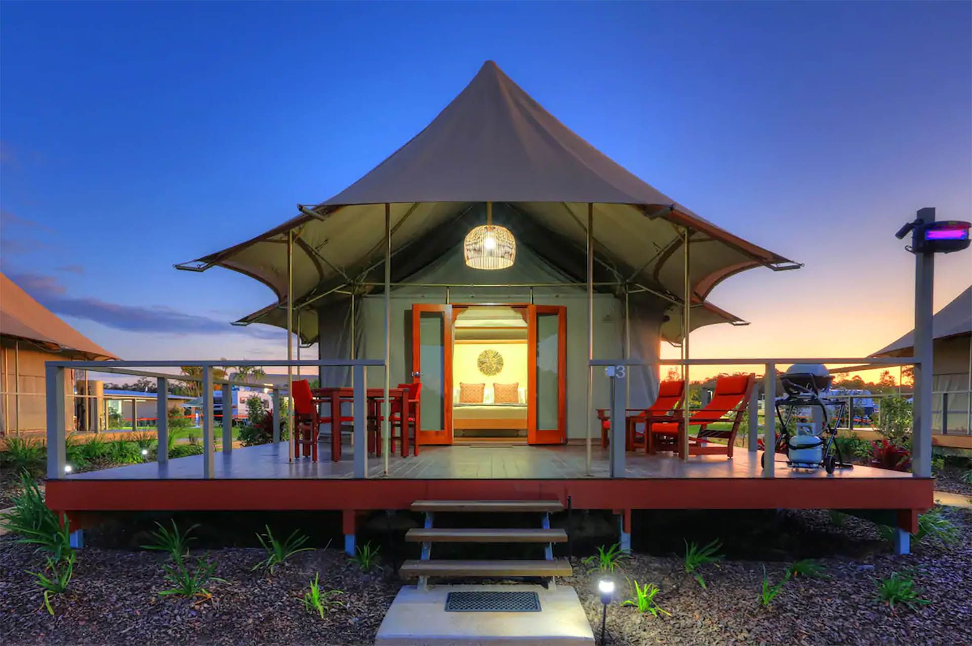 Colorful outdoor pavilion with red chairs and a central doorway at dusk