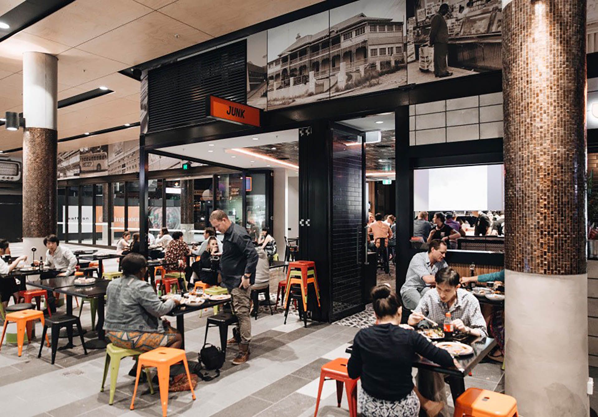 People dining in a modern restaurant with orange stools and black-and-white decor