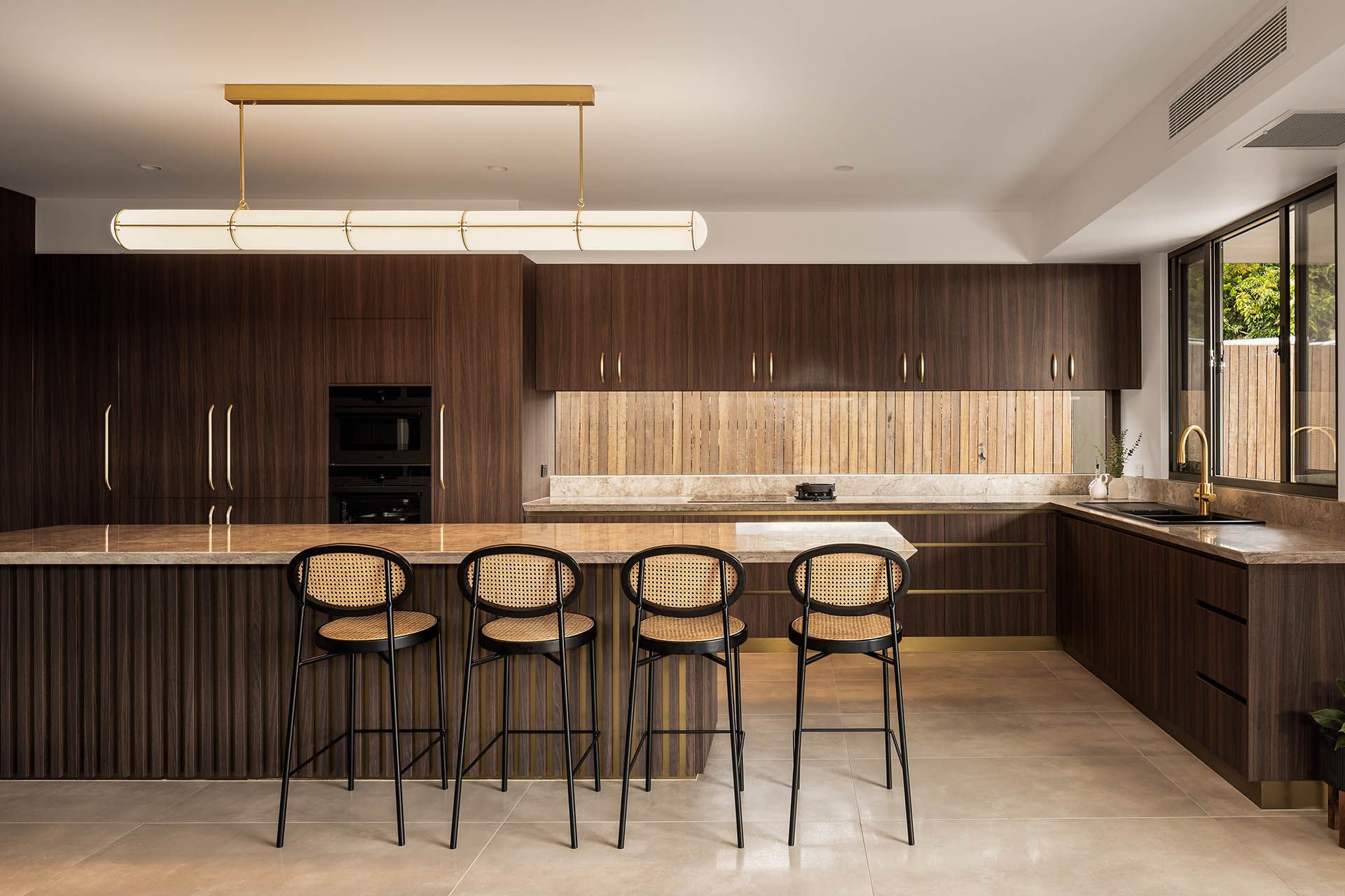 Modern kitchen with dark wood cabinetry, marble backsplash, island seating, and pendant lighting