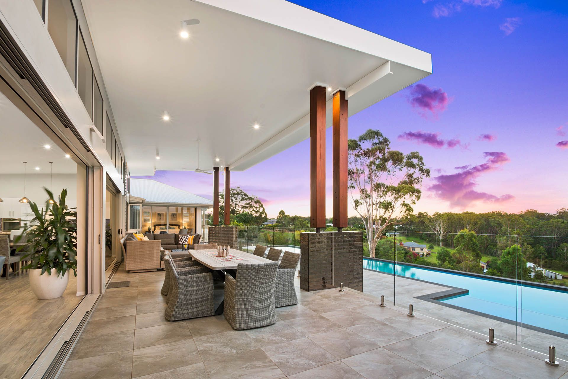 Modern patio with outdoor seating, pool, and sunset view over a lush landscape