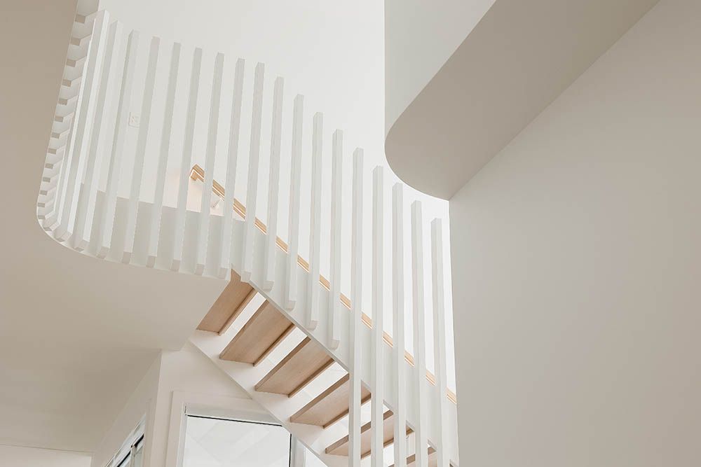 White staircase with vertical slat railing in a bright modern interior