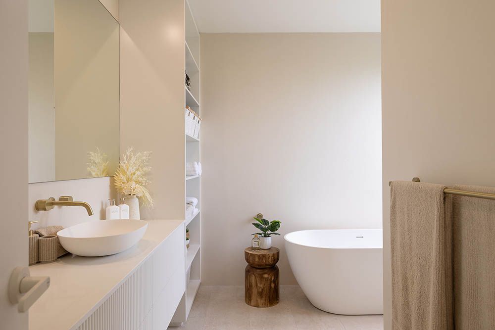Minimal beige bathroom with double sink, tub, and wood accents