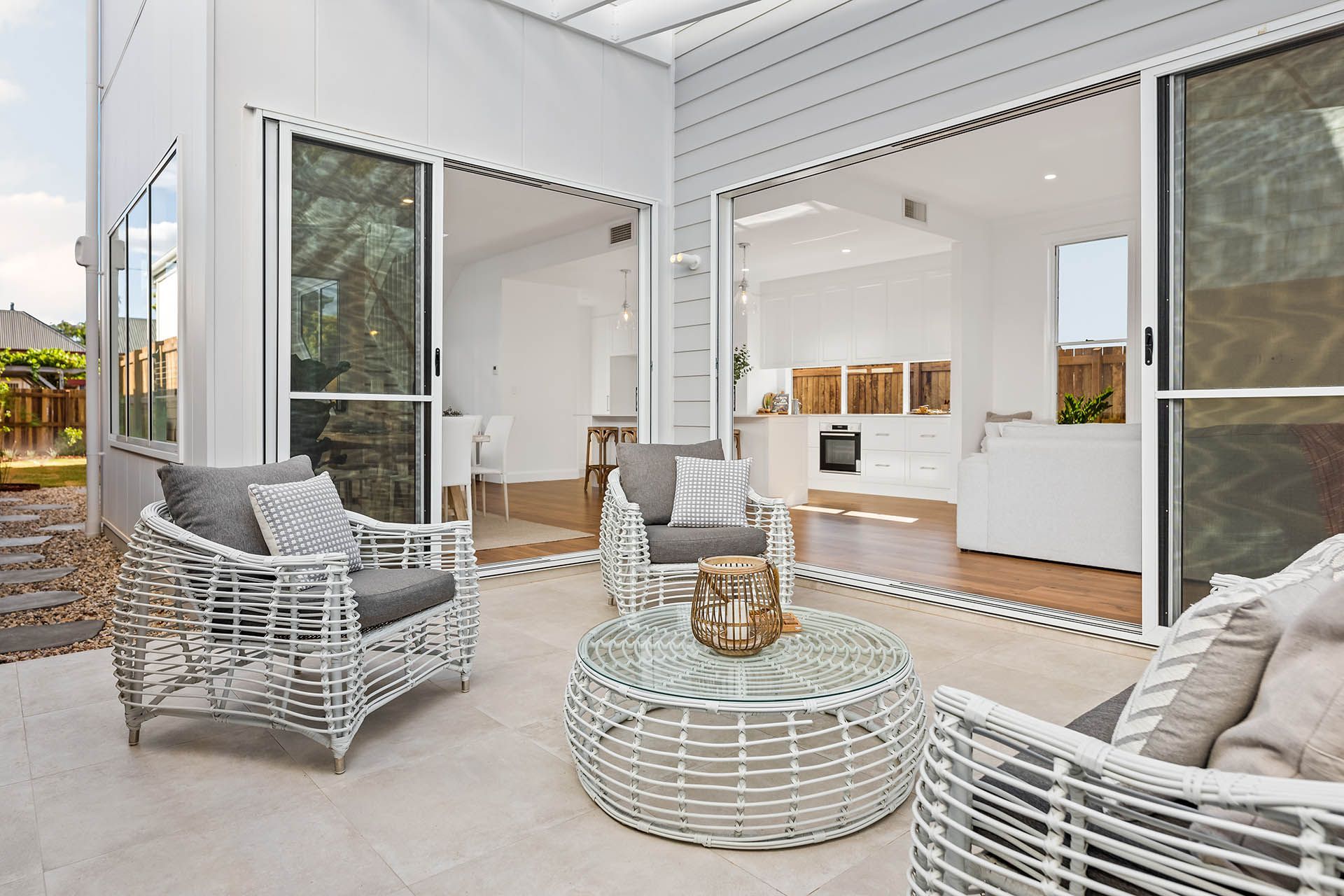 Bright white patio with wicker chairs, round table, and open doors to a modern living room