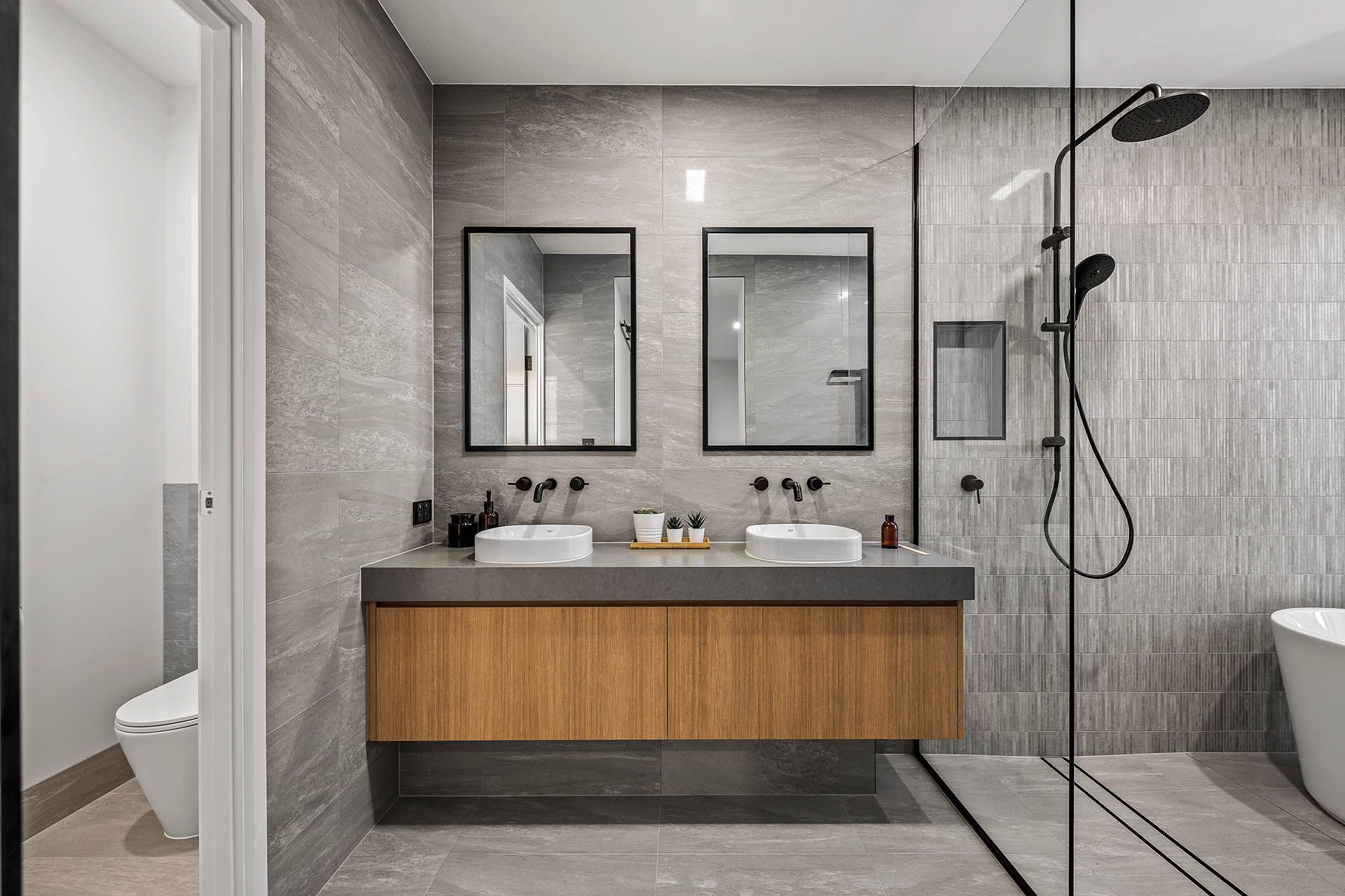 Modern gray bathroom with double vanity, mirrors, and walk-in shower
