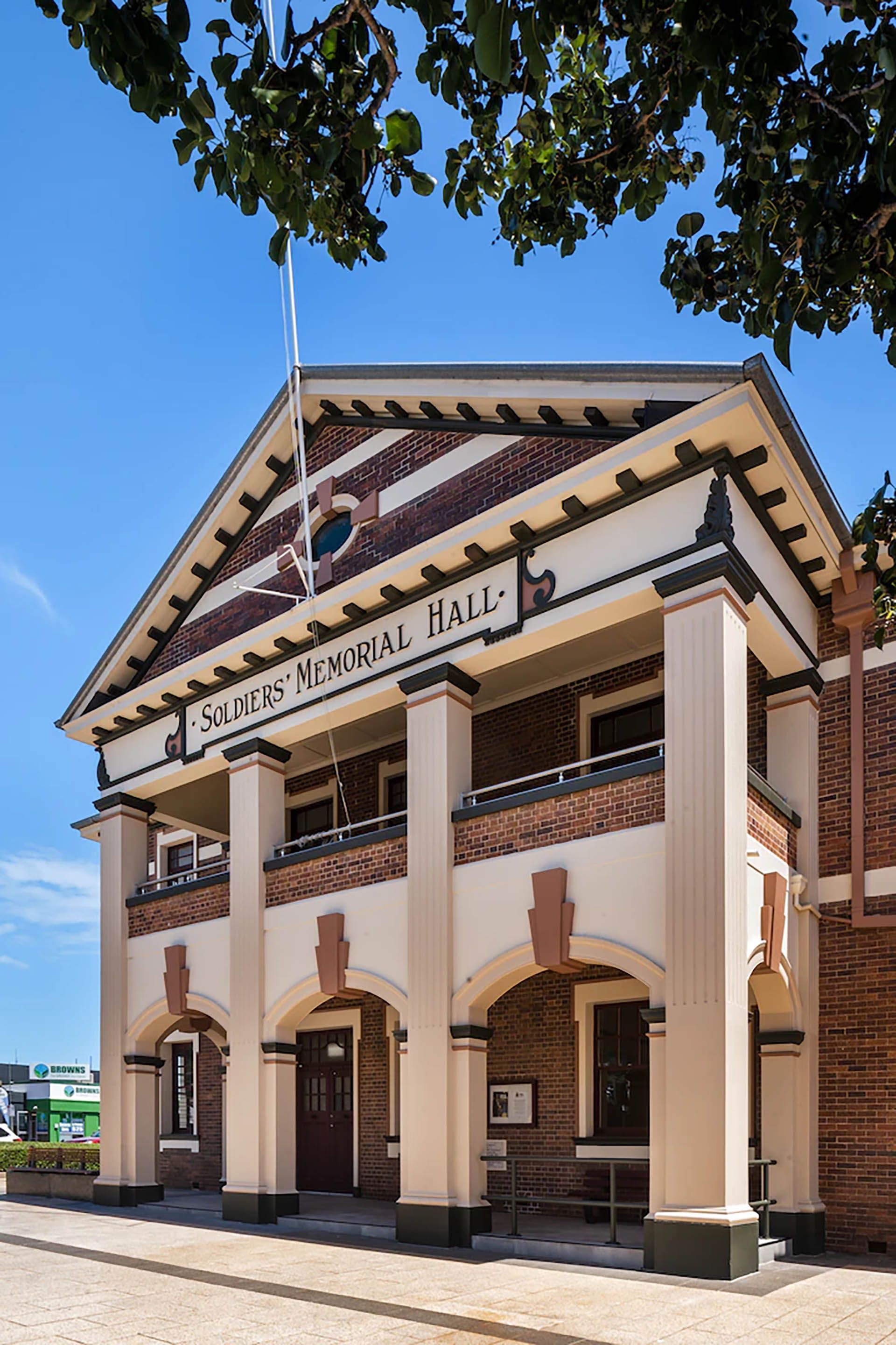 Historic town hall building with columns and arched entrance under a blue sky.