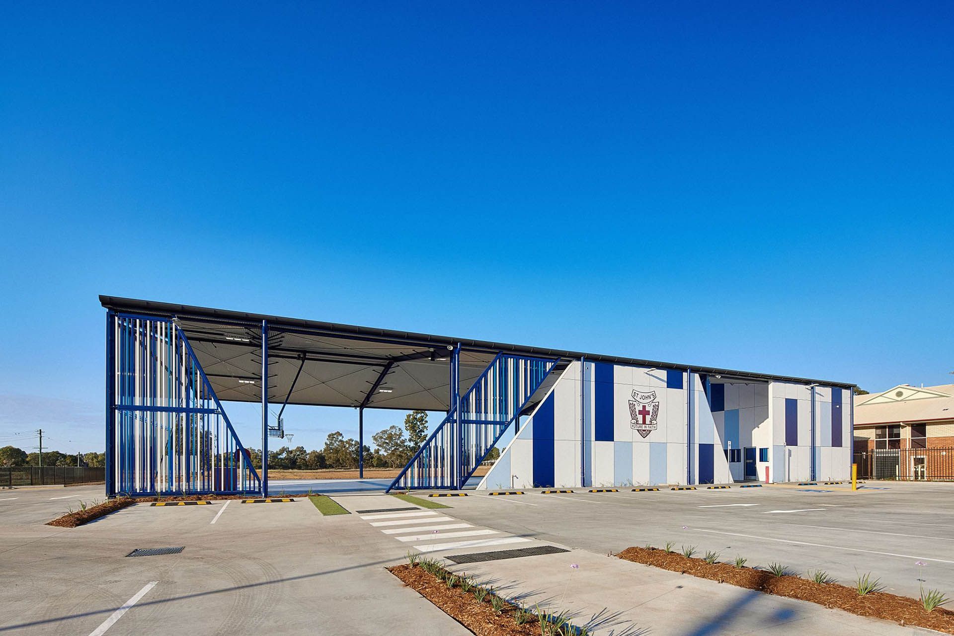 Blue-and-white modular building with a covered open frame under a clear sky.