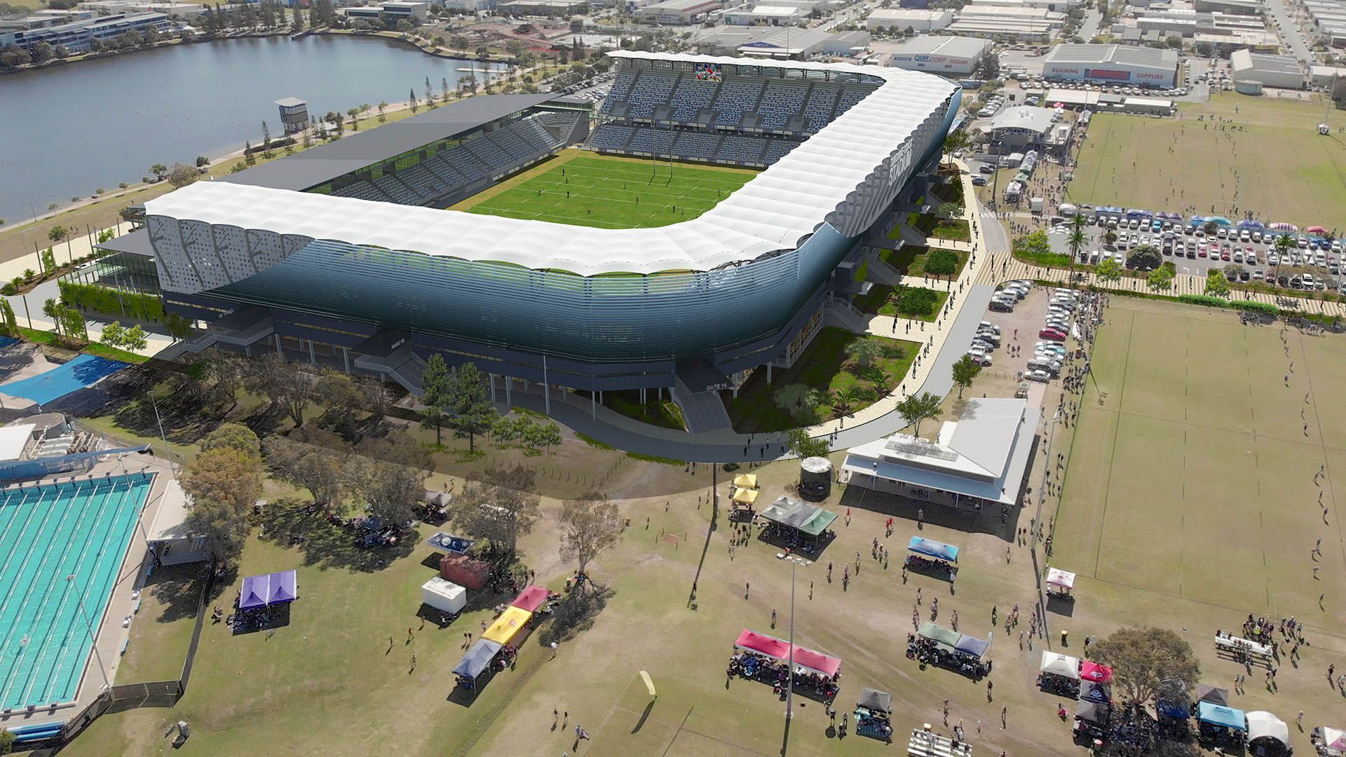 Aerial view of a modern stadium with a green field, surrounded by water, roads, and open parkland.
