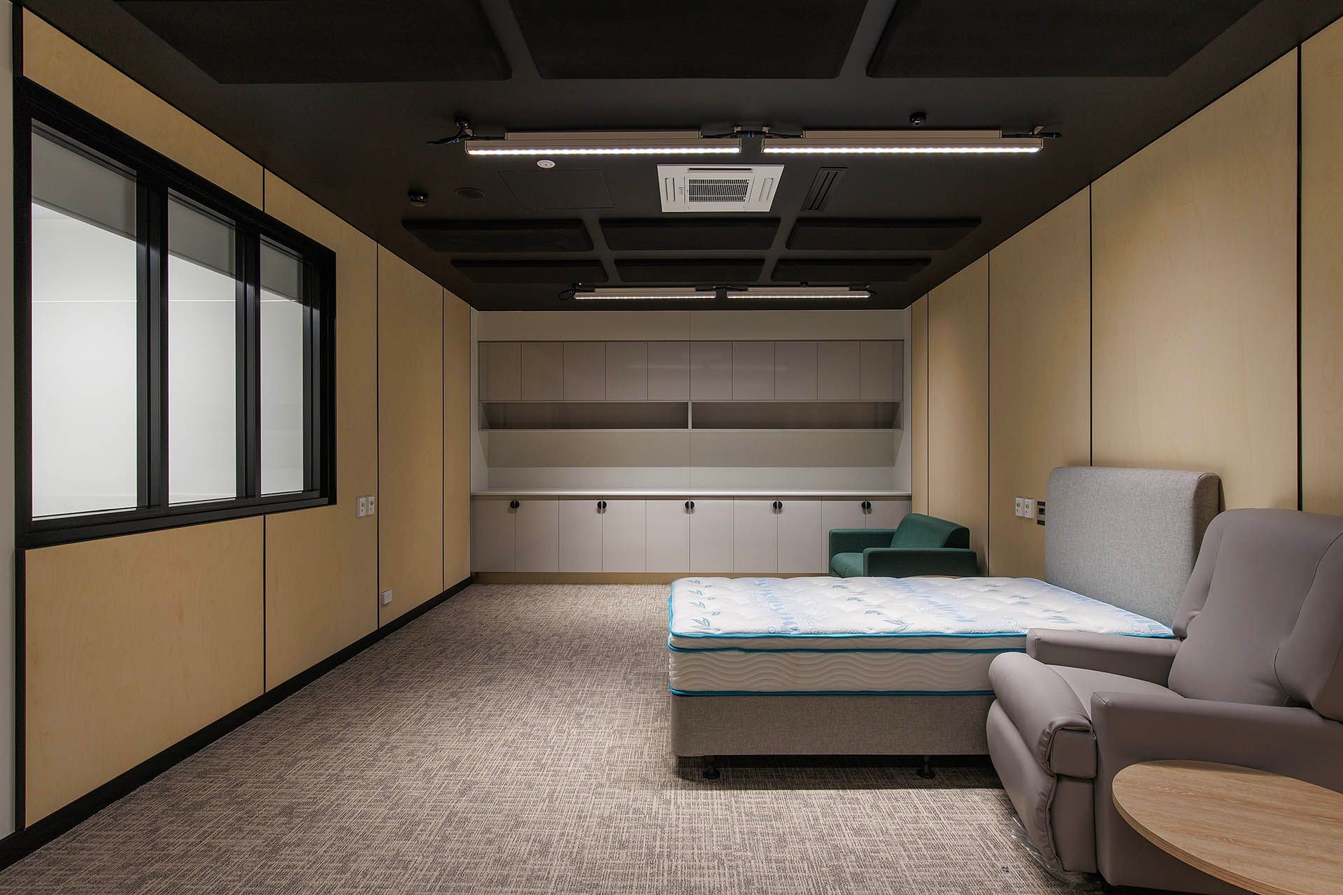 Modern minimalist bedroom with a bed, sofa, windows, and built-in cabinets.