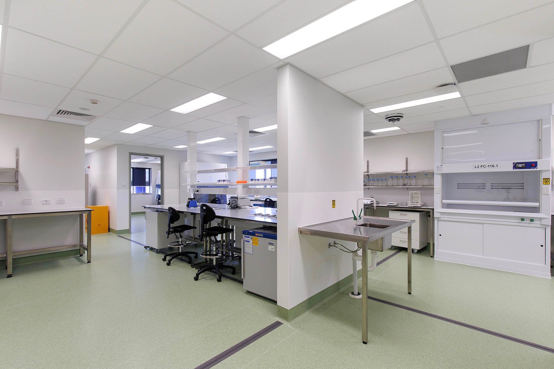 Bright modern laboratory with workbenches, equipment, and green flooring under white ceiling lights