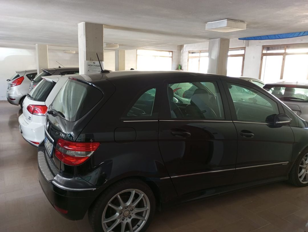 Un'auto nera è parcheggiata in un garage con altre auto