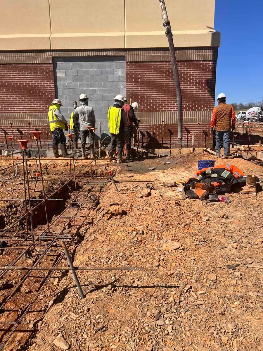 Construction workers in hard hats working beside a brick wall at a building site