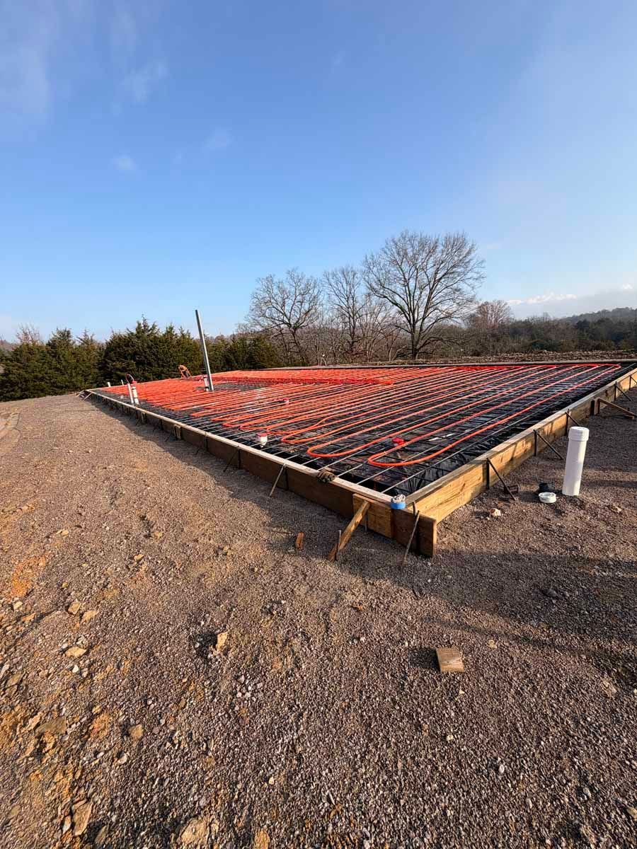 Gravel construction site with a large rebar foundation slab under an orange safety net