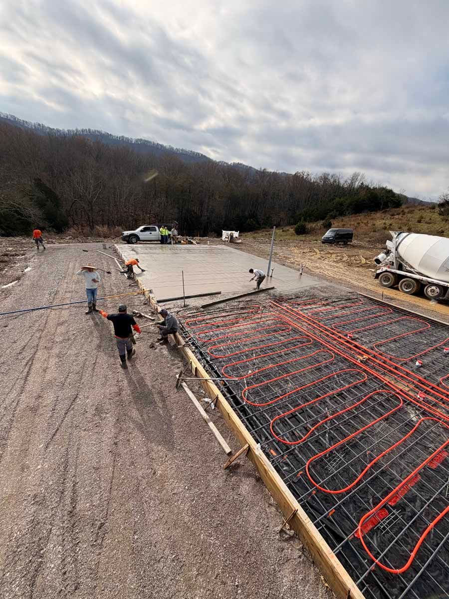 Construction site with rebar grid and workers on a gravel hillside under a cloudy sky