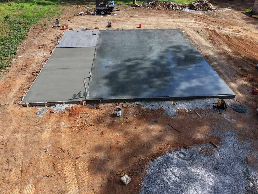 Freshly poured concrete slab at a construction site with formwork and dirt around it