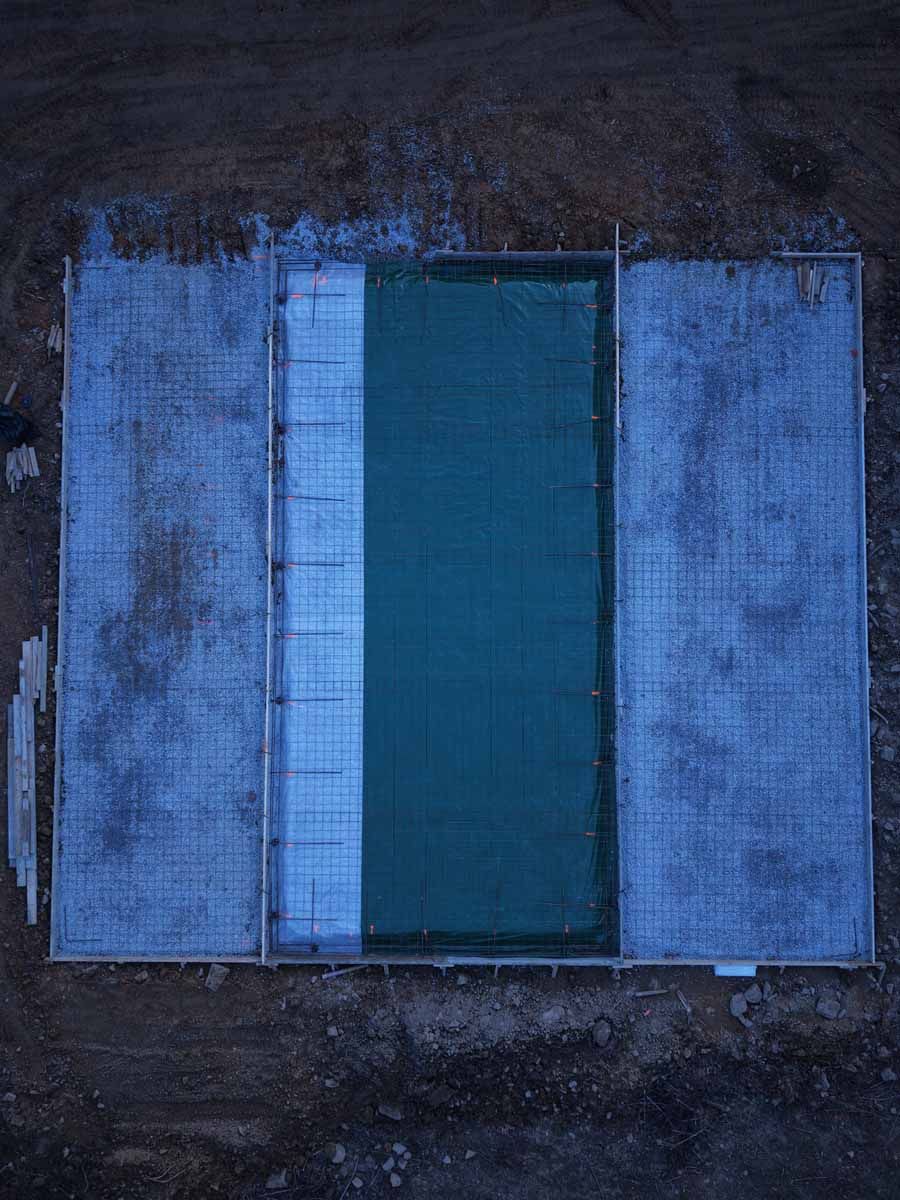Top-down view of a blue-green rectangular door or panel centered between two gray concrete slabs.