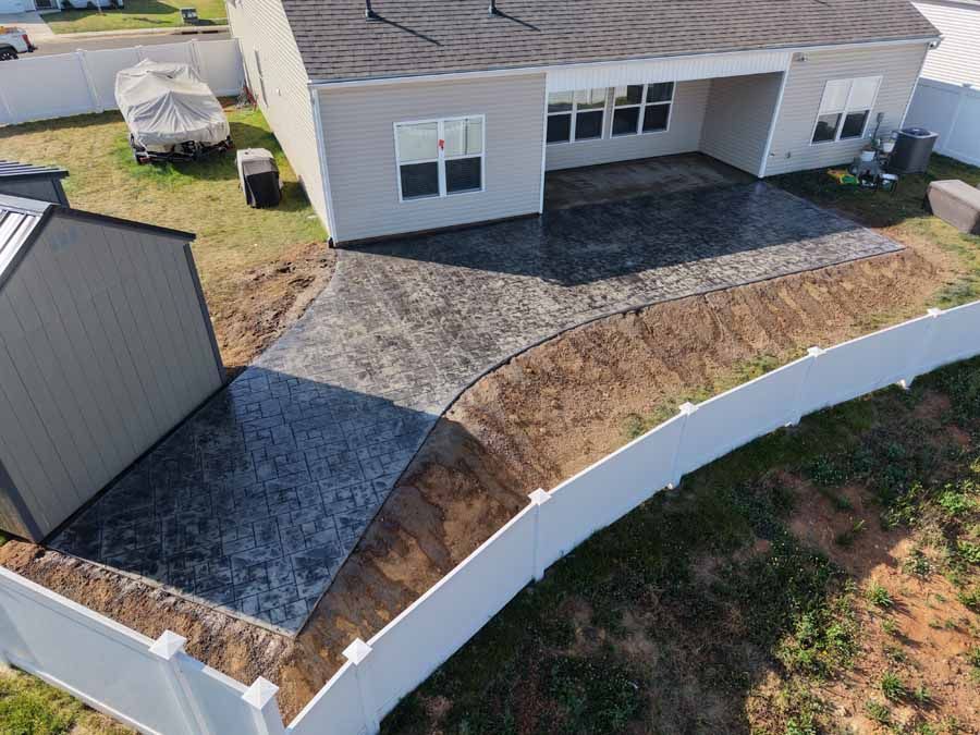 Backyard patio with gray pavers, white curved wall, and a modern house exterior