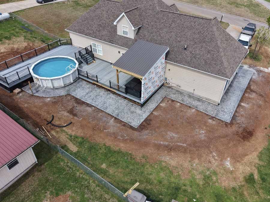 Aerial view of a house with a deck, above-ground pool, and fenced backyard under construction