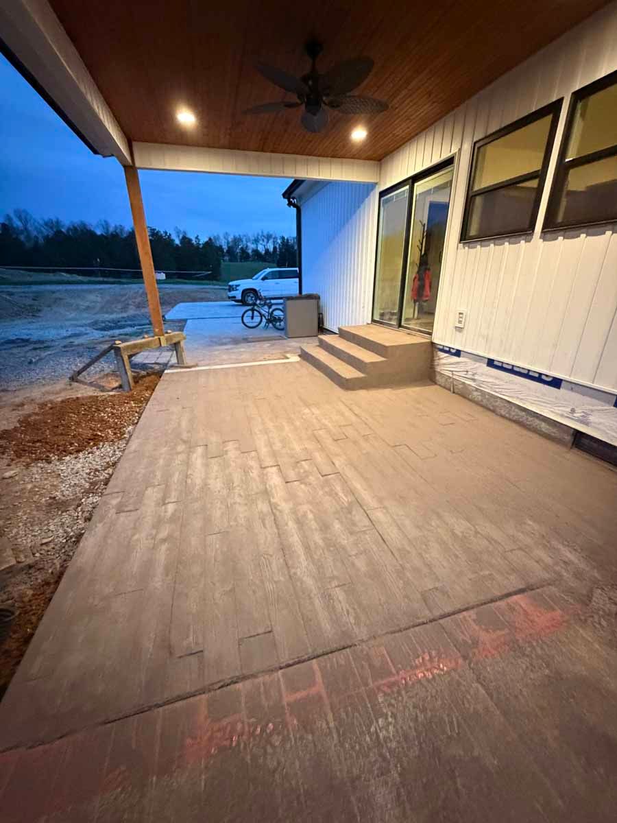 Covered porch at dusk with steps, a wooden ceiling, and a bicycle near the edge of a driveway