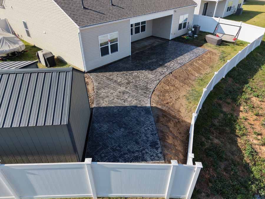 Backyard with white fence, gravel patio, gray shed, and beige house seen from above