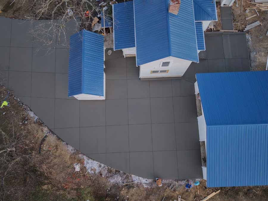 Aerial view of buildings with blue roofs around a paved courtyard and surrounding trees