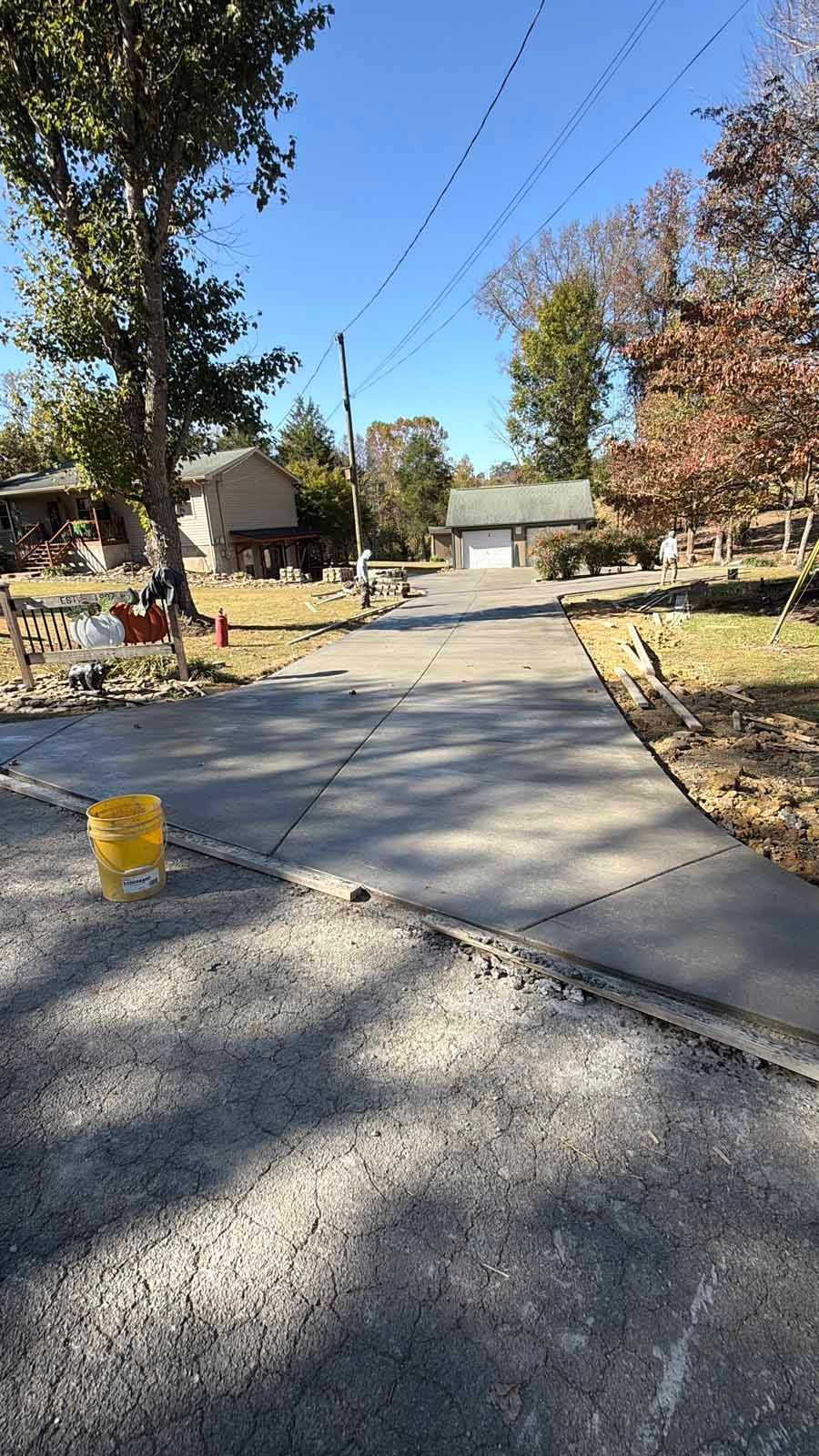 Concrete driveway leading to a house in a quiet suburban yard on a sunny day