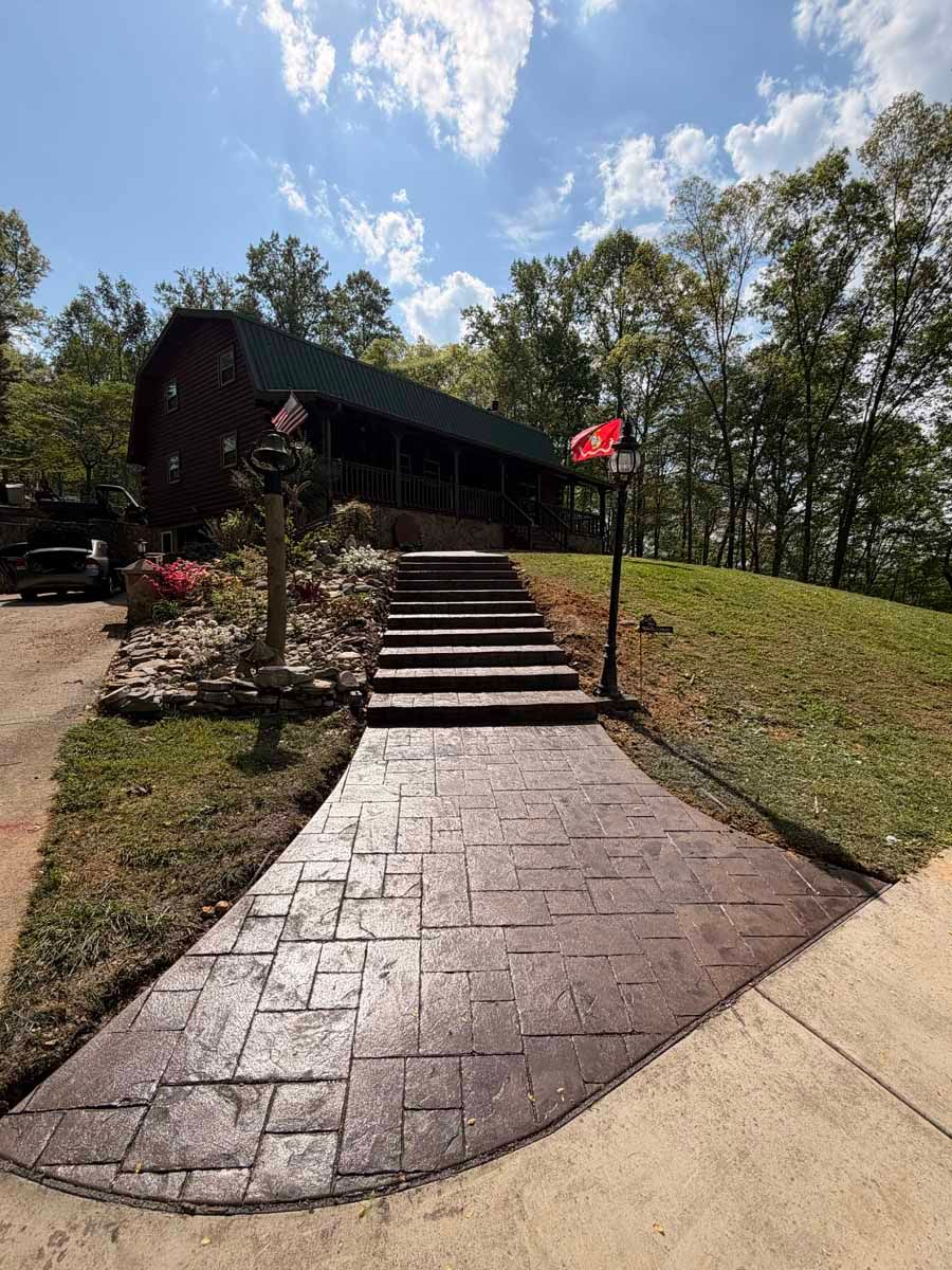 Brick walkway with steps leading to a cabin on a grassy hill, with a Canadian flag and trees nearby.