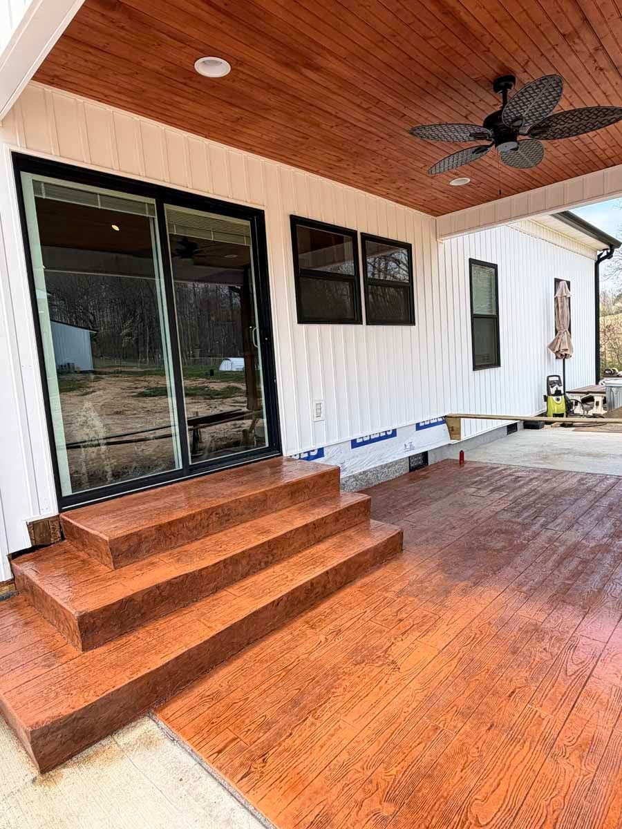Covered patio with wood deck, steps, sliding glass door, white exterior wall, and ceiling fan