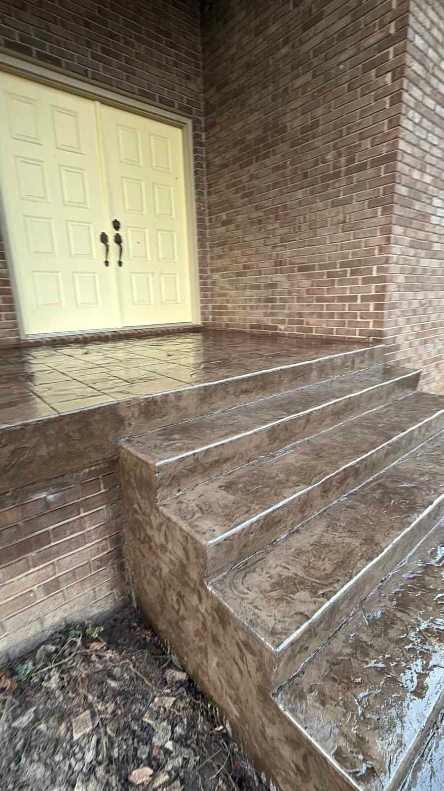 Brick entryway with wet steps and a cream double door at the top of the stairs