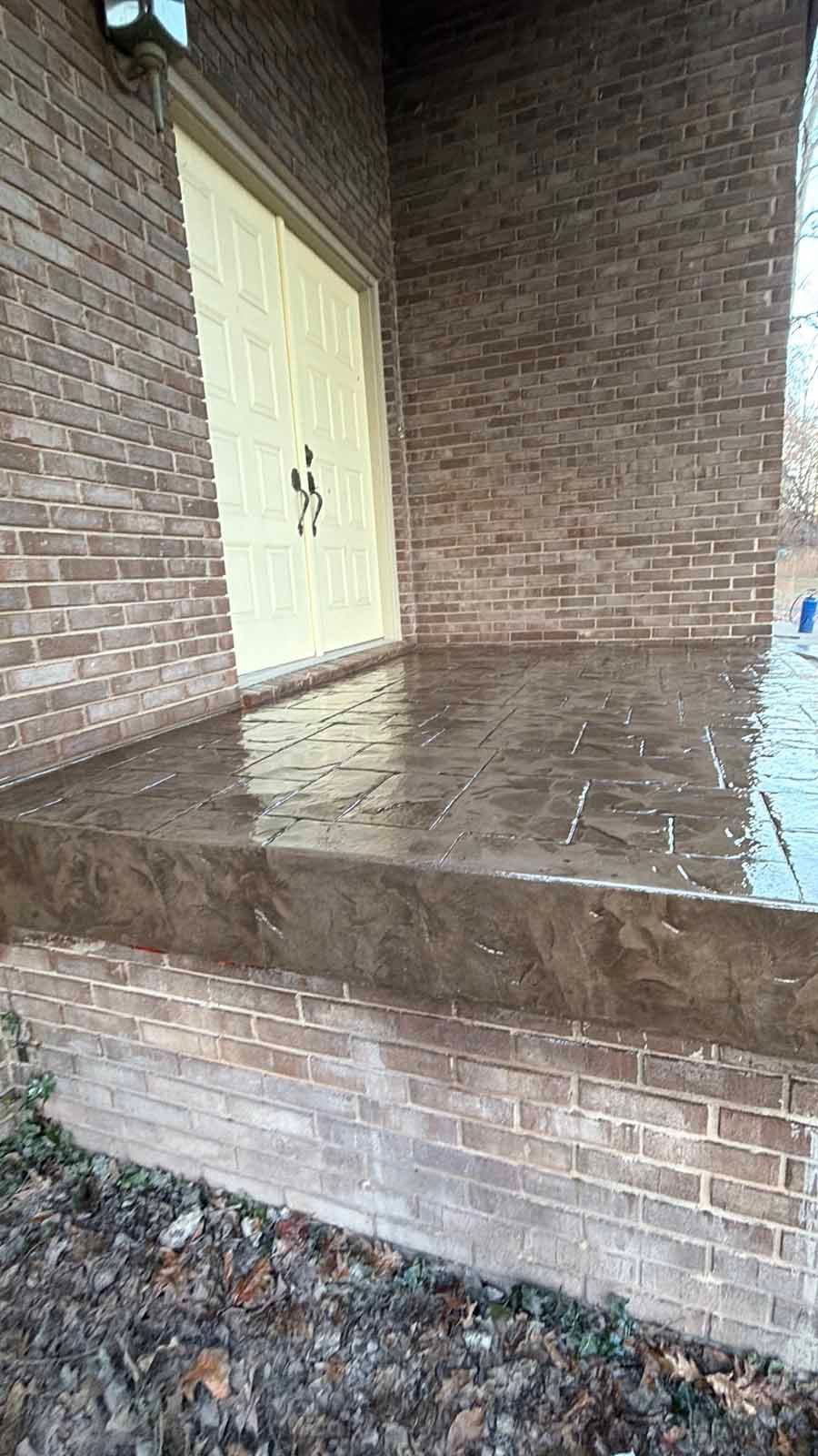 Brick porch with a wet tiled floor and a white door under a covered entryway