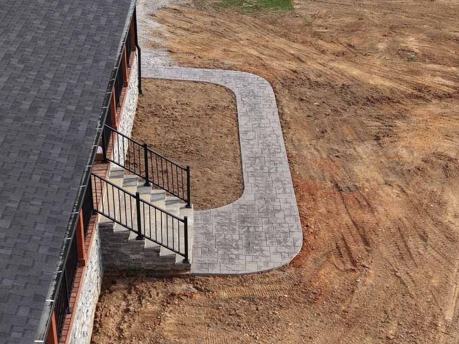 Brick walkway and steps beside a building, curving around a bare dirt yard.