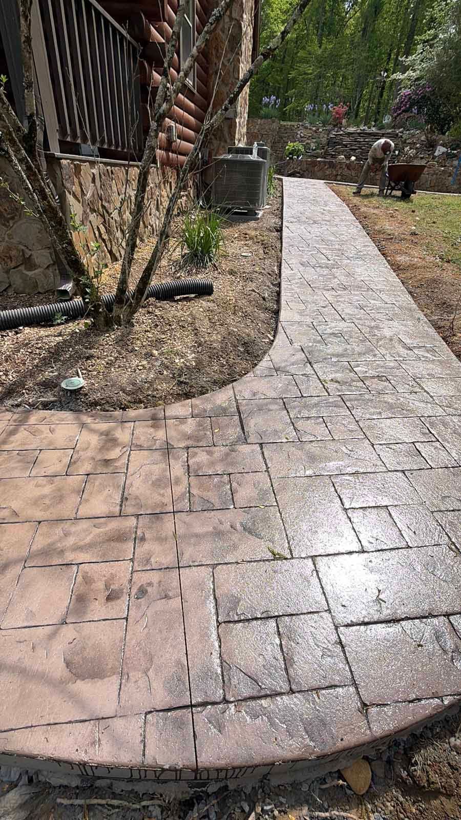 Wet stone walkway curving past a rustic building and garden trees