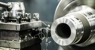 Torno de metal mecanizando una pieza cilíndrica, produciendo virutas de metal.