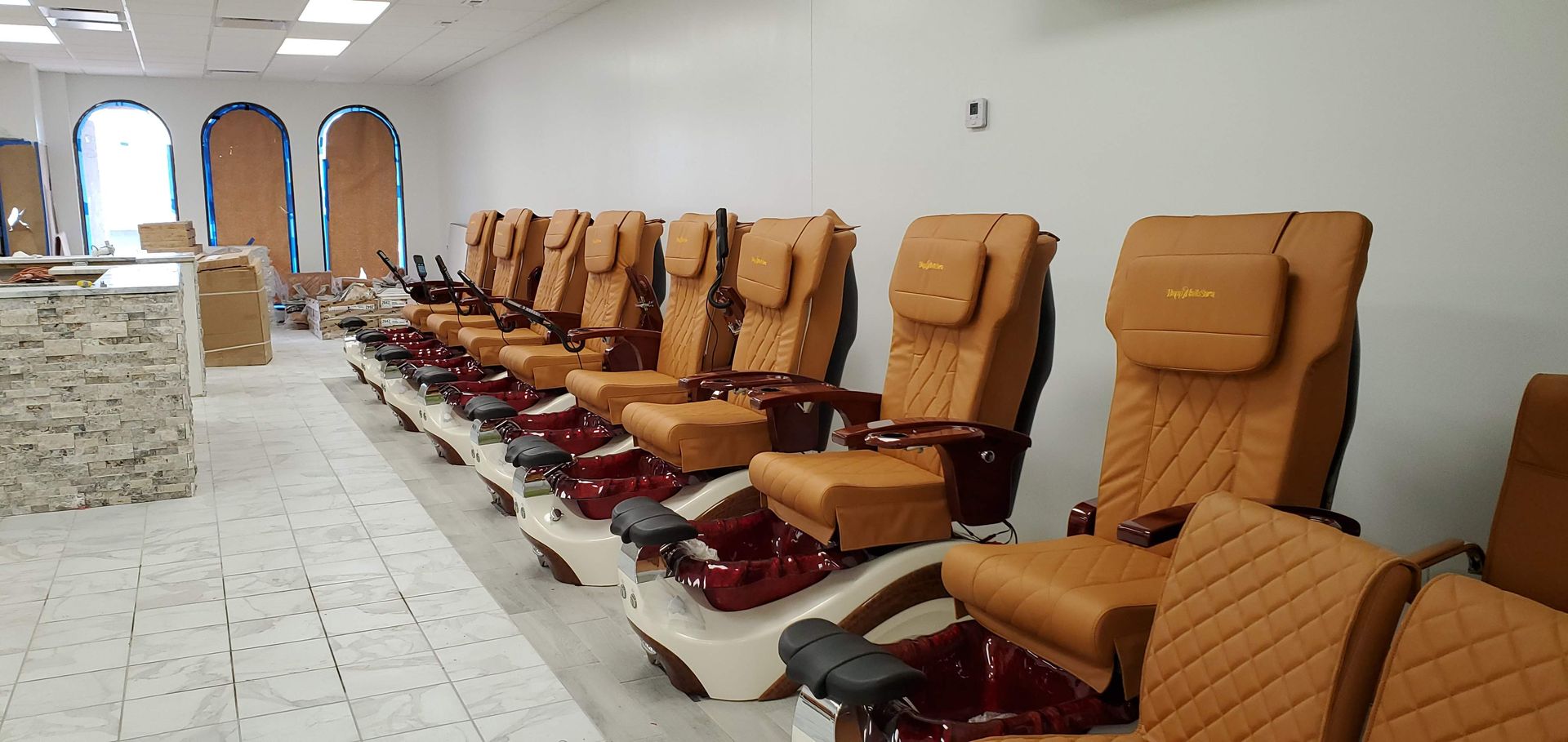 A row of nail salon chairs are lined up in a room.