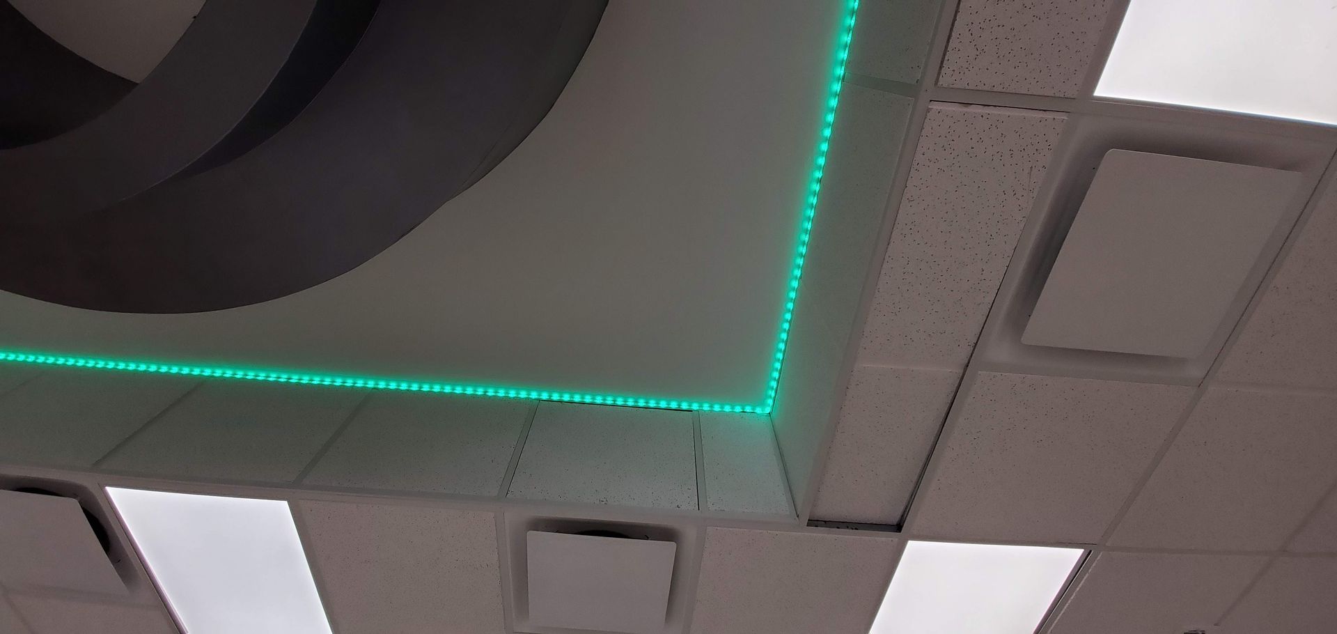 A close up of a ceiling with a green light on it.