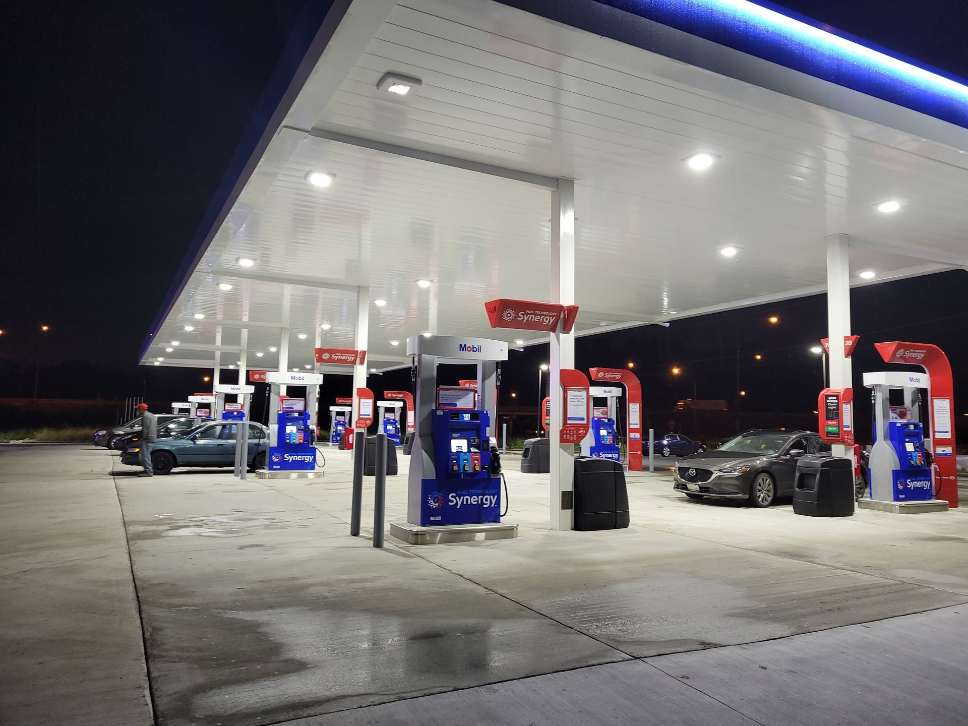 A gas station at night with cars parked in front of it