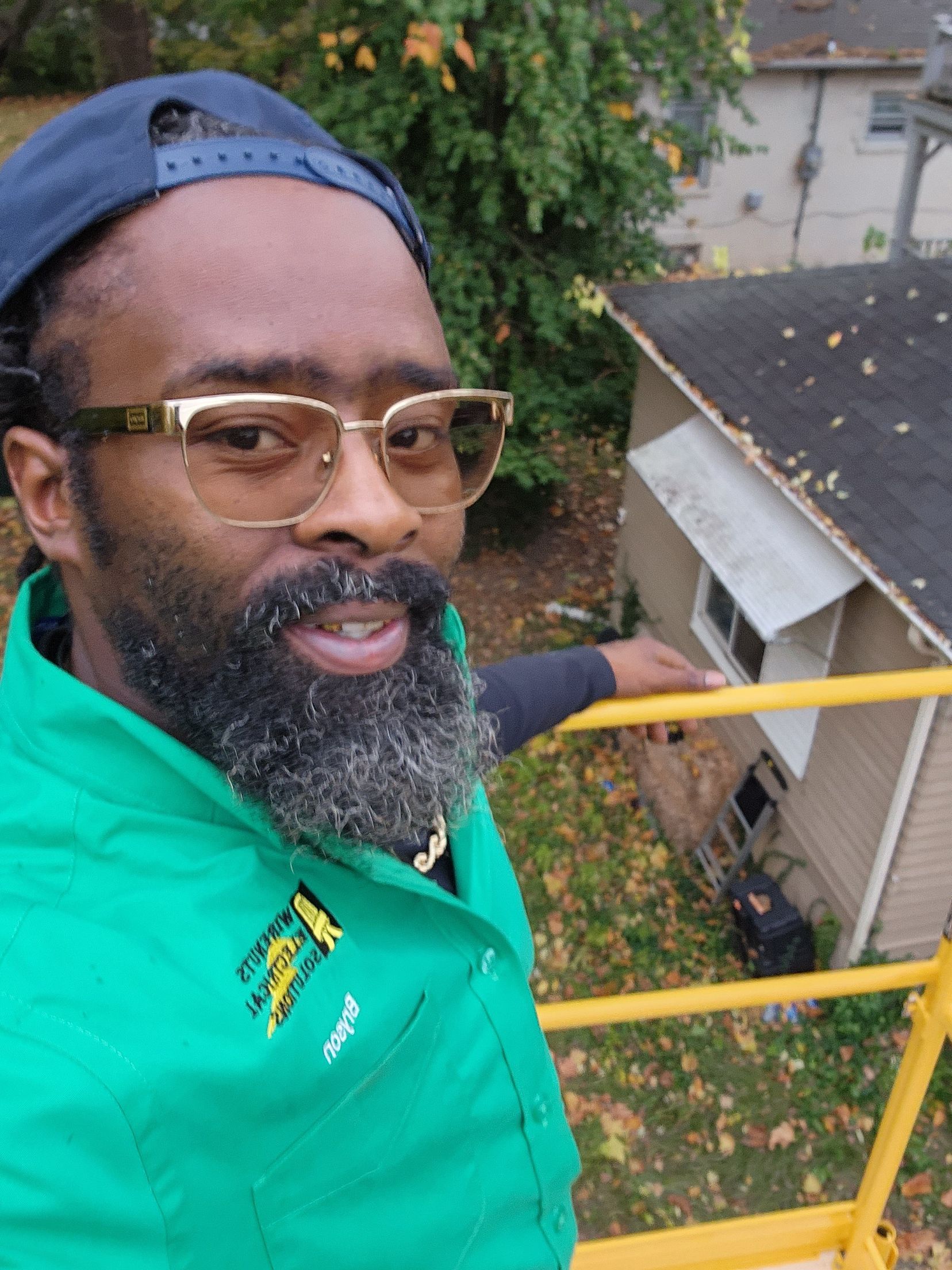 A man with a beard and glasses is standing in front of a house.