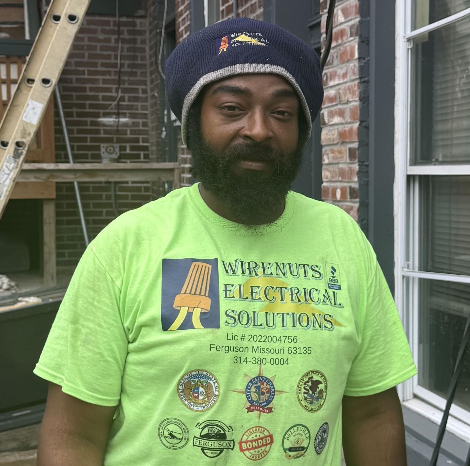 A man wearing a green shirt that says wirenuts & electrical solutions